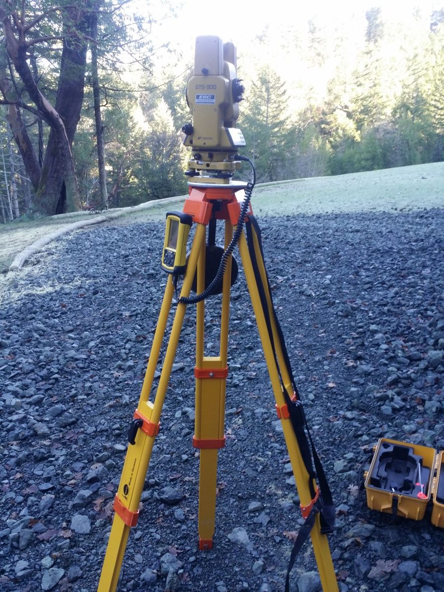 Total station set up over gravel on a wooded survey site